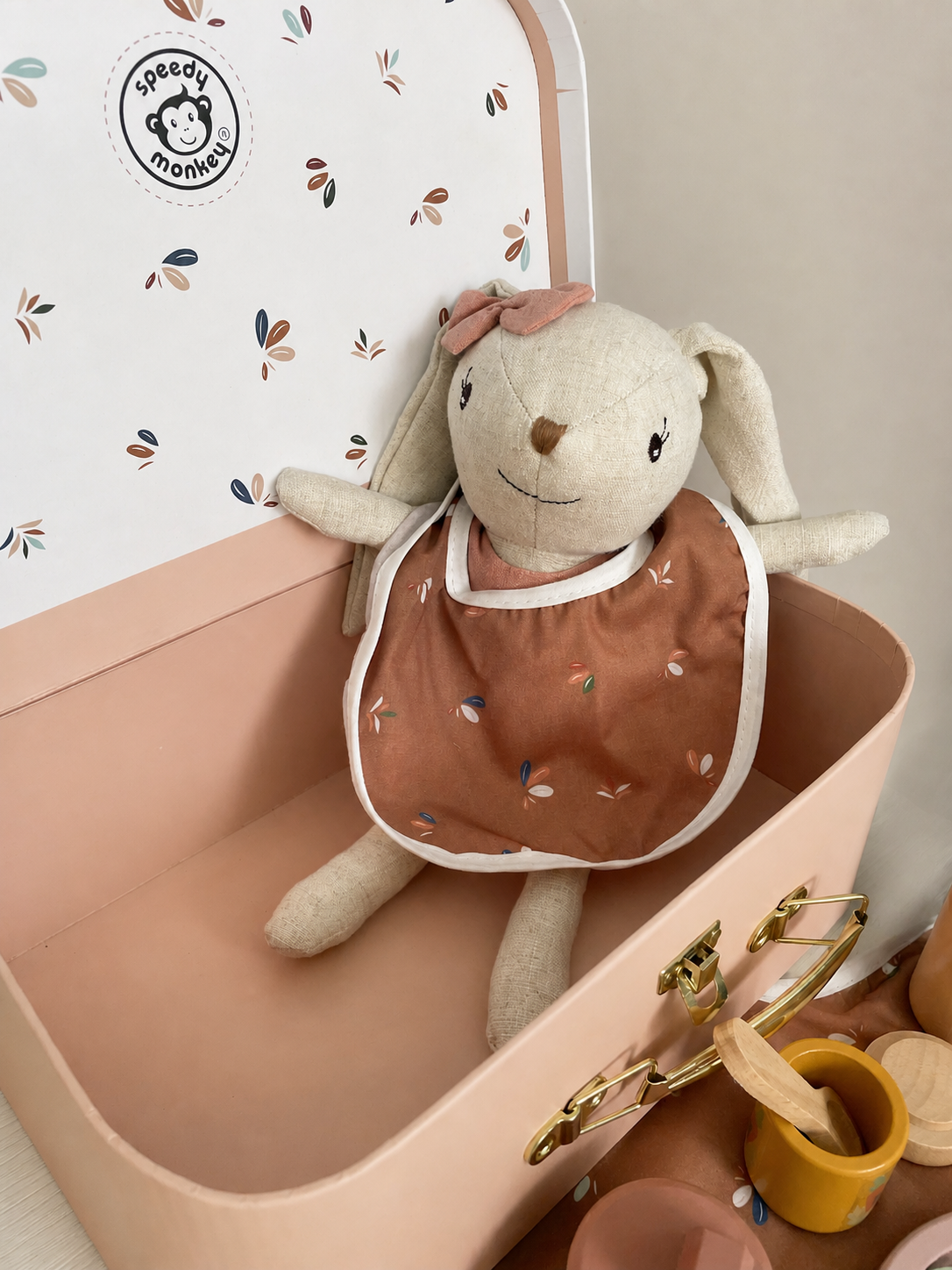 Poupée lapin Speedy Monkey avec bavoir à motifs dans sa valisette rose